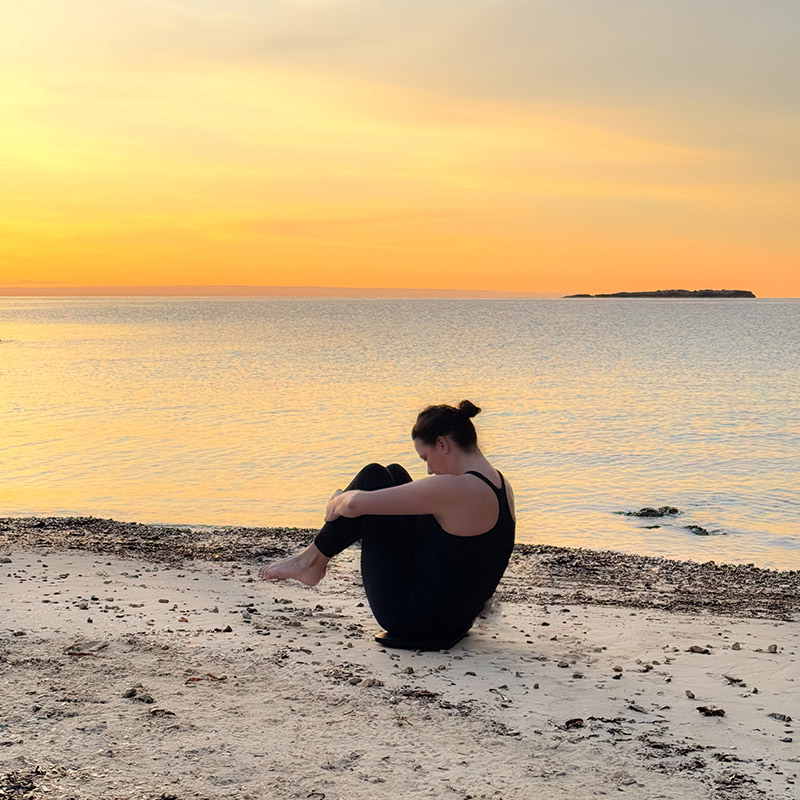 Pilates Rolling like a ball Vorbereitung am Strand